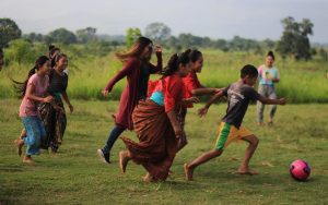 A group of eight children playing soccer on a grass field