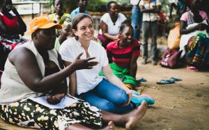 A group of women sitting on the ground and speaking with Oxfam Canada's Executive Director