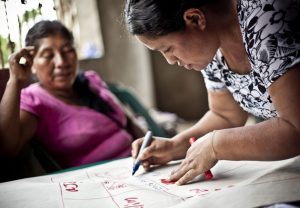 Two women writing instructions onto a large piece of chart paper